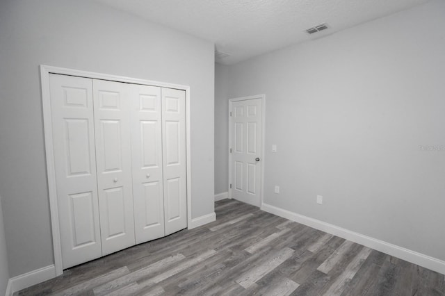 unfurnished bedroom with wood-type flooring, a textured ceiling, and a closet