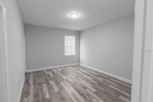 spare room featuring wood-type flooring and a textured ceiling