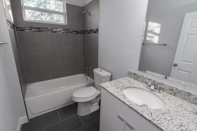 full bathroom featuring tile floors, tiled shower / bath, toilet, and vanity with extensive cabinet space