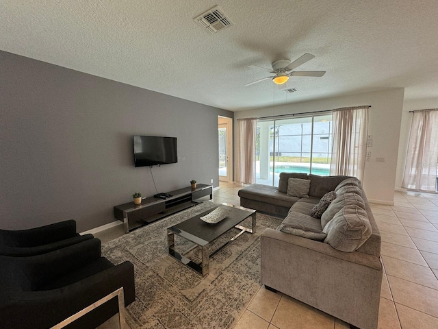 living room featuring a textured ceiling, ceiling fan, and light tile floors