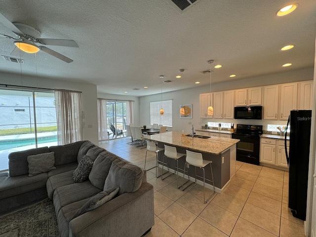 kitchen with hanging light fixtures, ceiling fan, light tile floors, and black appliances