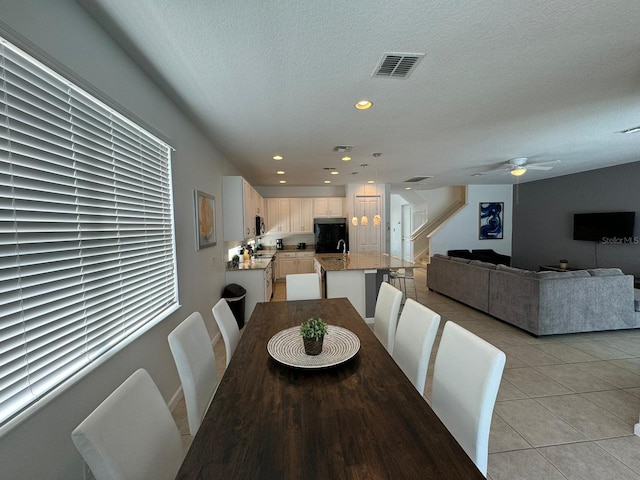 tiled dining space featuring a textured ceiling and ceiling fan