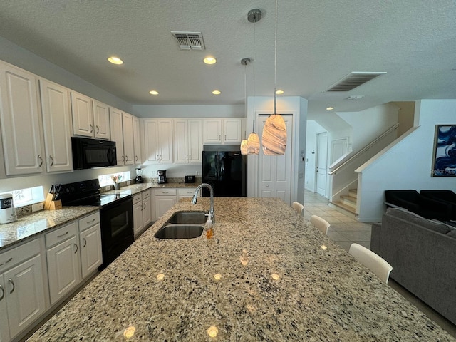 kitchen featuring pendant lighting, light tile flooring, white cabinetry, black appliances, and sink