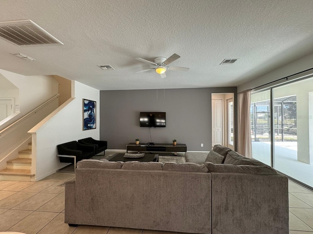 living room featuring ceiling fan, light tile floors, and a textured ceiling