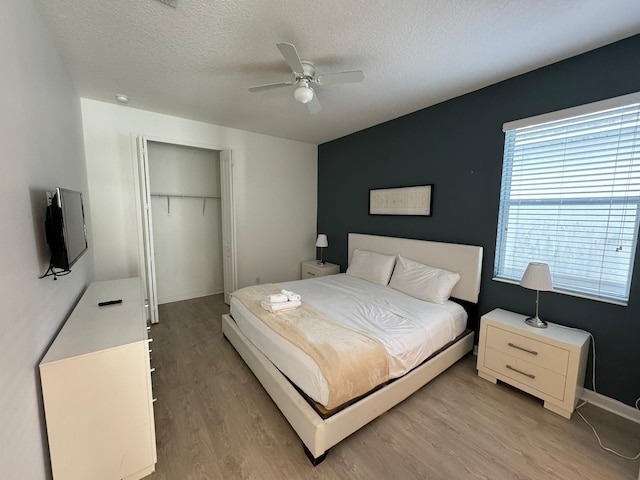 bedroom featuring light hardwood / wood-style flooring, ceiling fan, a textured ceiling, and a closet