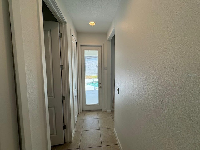 hallway featuring light tile floors and a textured ceiling