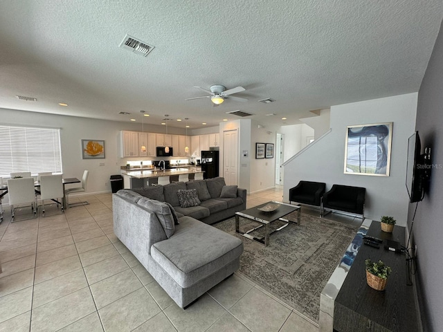 tiled living room with ceiling fan, a wealth of natural light, and a textured ceiling