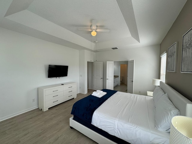 bedroom with ceiling fan, a raised ceiling, and hardwood / wood-style flooring