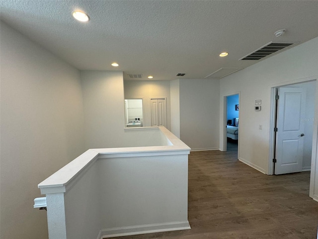 hall featuring a textured ceiling and dark hardwood / wood-style flooring