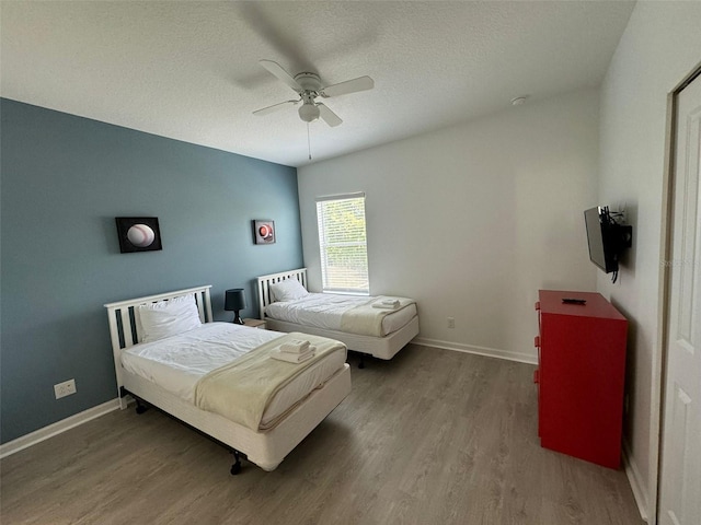 bedroom with hardwood / wood-style floors, ceiling fan, and a textured ceiling