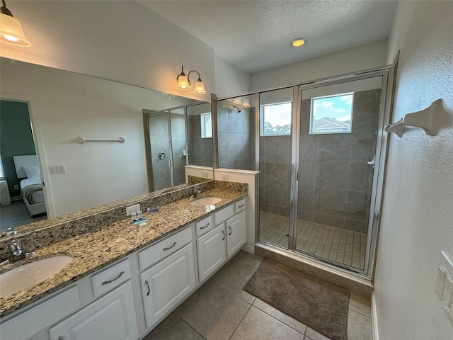 bathroom featuring double sink vanity, tile floors, a shower with shower door, and a textured ceiling