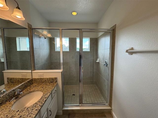 bathroom featuring a shower with door, a textured ceiling, and large vanity