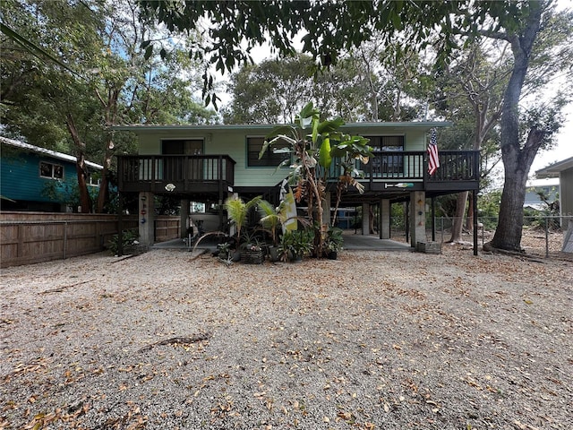 view of front of property with a carport, driveway, a deck, and fence