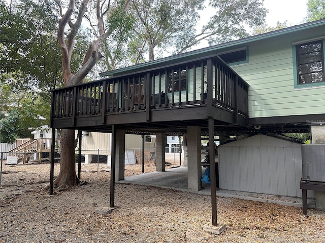 rear view of property featuring an outbuilding, a patio, a deck, fence, and a storage unit