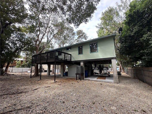 back of house featuring an outbuilding, a storage shed, fence, a carport, and driveway