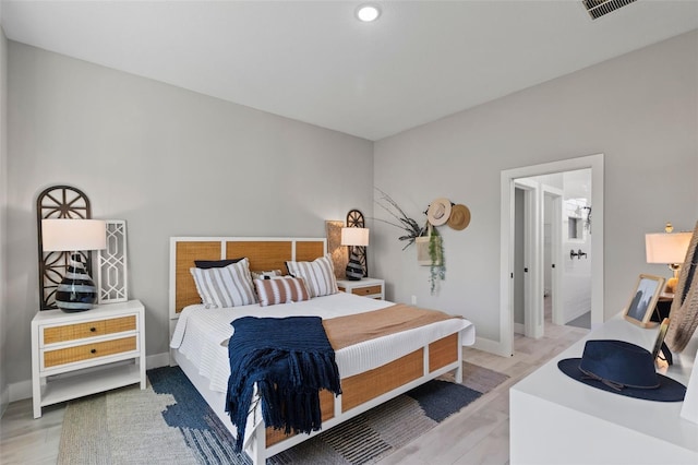 bedroom with ensuite bathroom and hardwood / wood-style flooring