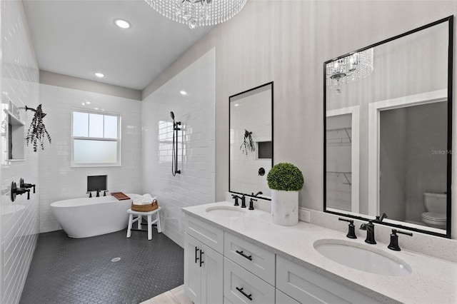 bathroom with tile patterned flooring, vanity, a bath, and a notable chandelier