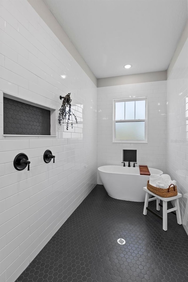 bathroom with tile patterned flooring and a tub to relax in