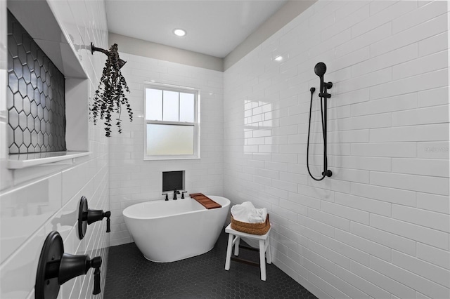 bathroom with tile patterned flooring, a bath, and tile walls