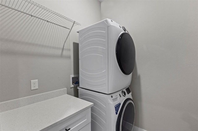 clothes washing area featuring cabinets and stacked washer and dryer