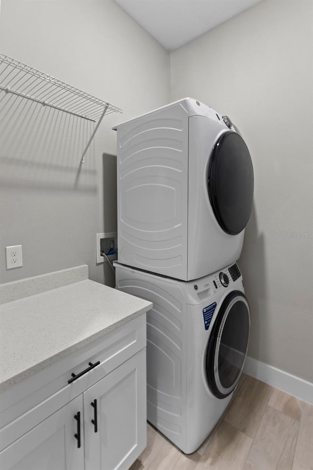 laundry room with cabinets and stacked washer and clothes dryer