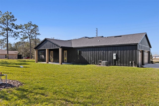 rear view of house featuring a yard, a garage, and central AC unit