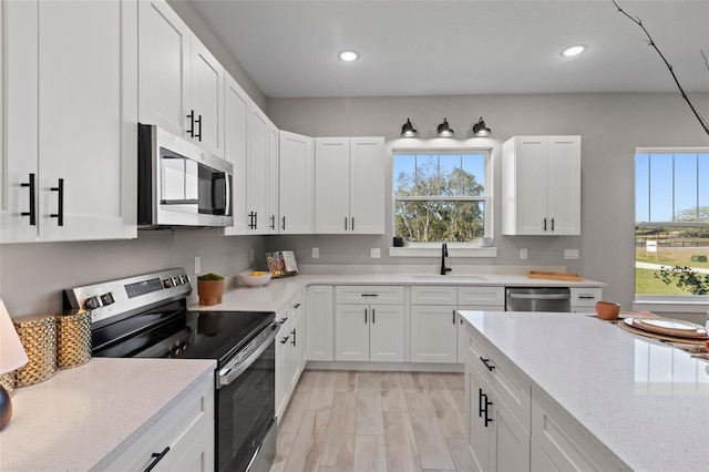 kitchen with white cabinets, plenty of natural light, light stone countertops, and appliances with stainless steel finishes