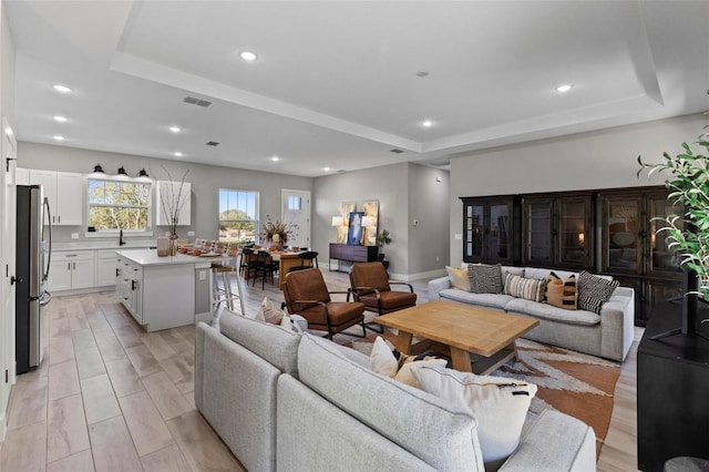 living room with a raised ceiling and sink