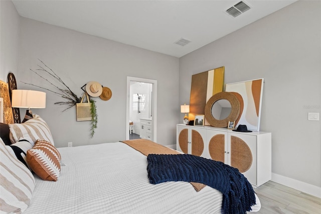 bedroom with connected bathroom and light hardwood / wood-style floors