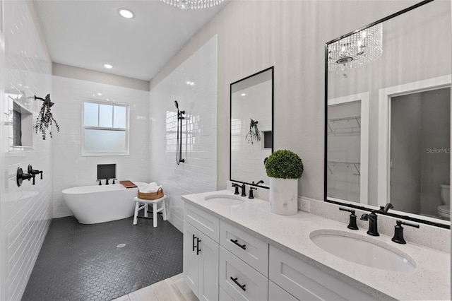 bathroom featuring an inviting chandelier, tile patterned flooring, a tub to relax in, vanity, and tile walls