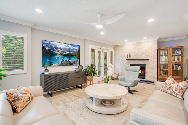 living room with crown molding, a large fireplace, light hardwood / wood-style floors, and a textured ceiling