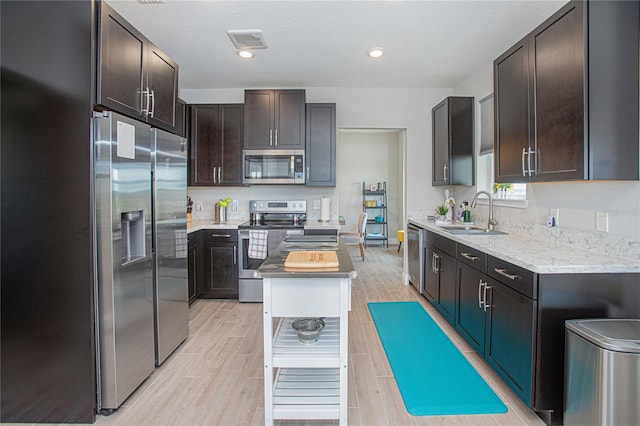 kitchen with dark brown cabinets, appliances with stainless steel finishes, sink, and a kitchen island