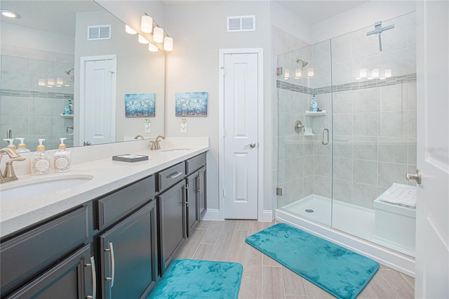 bathroom featuring a shower with shower door, double vanity, and tile floors