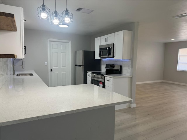 kitchen with appliances with stainless steel finishes, backsplash, white cabinets, sink, and light wood-type flooring