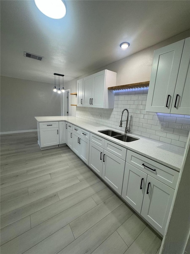 kitchen with tasteful backsplash, hanging light fixtures, white cabinets, and sink