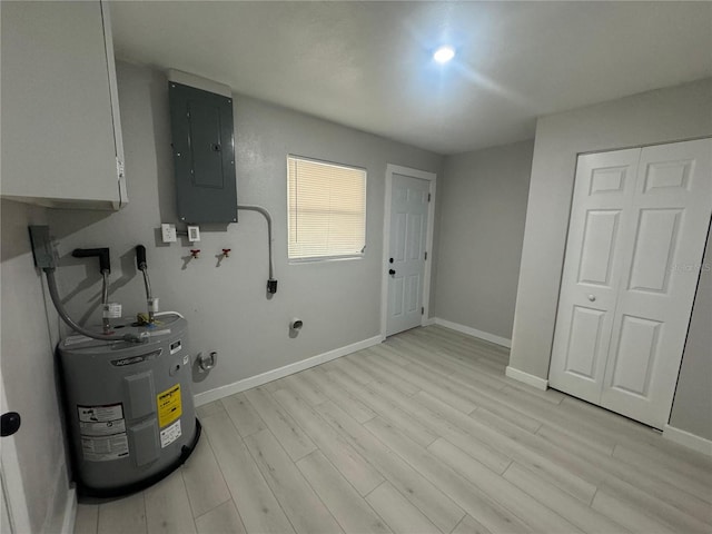 clothes washing area with light hardwood / wood-style floors, water heater, and cabinets