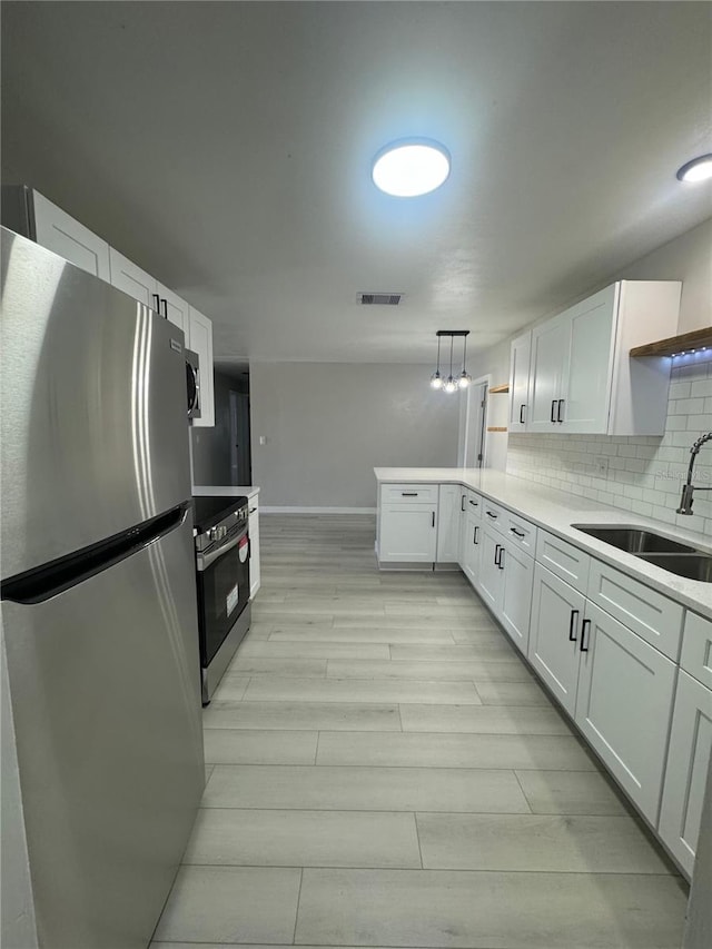 kitchen with tasteful backsplash, appliances with stainless steel finishes, pendant lighting, and white cabinets