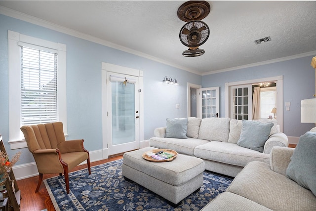 living room featuring ornamental molding, wood-type flooring, and a textured ceiling