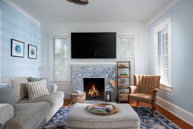 living room with ornamental molding, plenty of natural light, hardwood / wood-style flooring, and a tiled fireplace