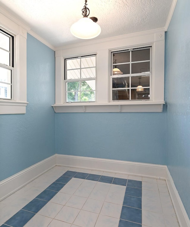 spare room featuring crown molding, tile floors, and a textured ceiling