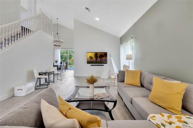 living room featuring high vaulted ceiling, an inviting chandelier, and light hardwood / wood-style flooring