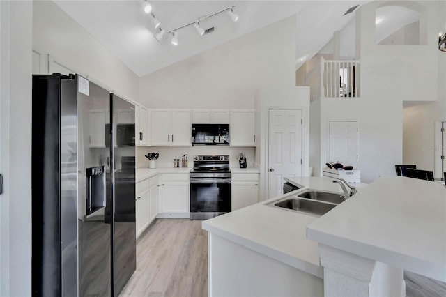 kitchen with stainless steel appliances, rail lighting, high vaulted ceiling, sink, and white cabinetry