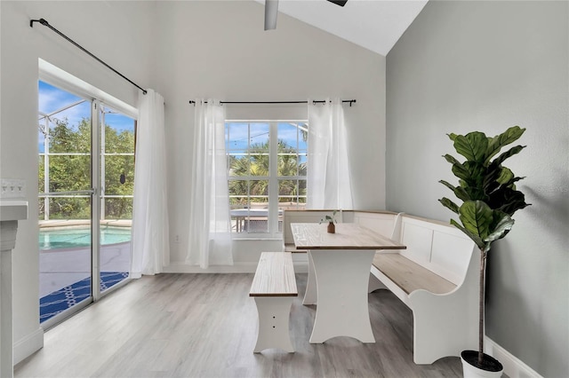 unfurnished dining area featuring high vaulted ceiling, ceiling fan, and light hardwood / wood-style flooring