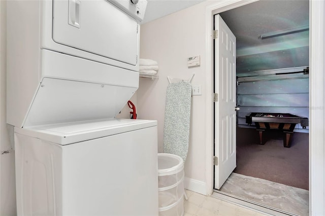 laundry area with stacked washing maching and dryer and light tile flooring