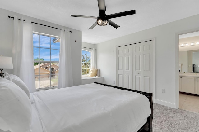 carpeted bedroom featuring a closet, ceiling fan, multiple windows, and ensuite bathroom