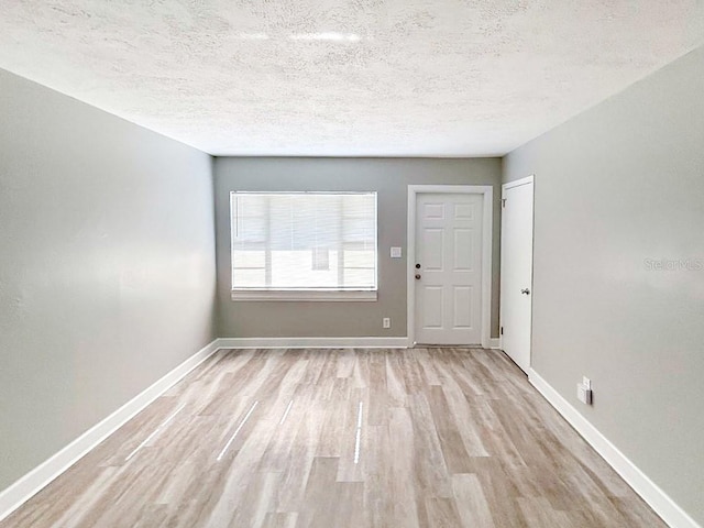 empty room with light hardwood / wood-style floors and a textured ceiling