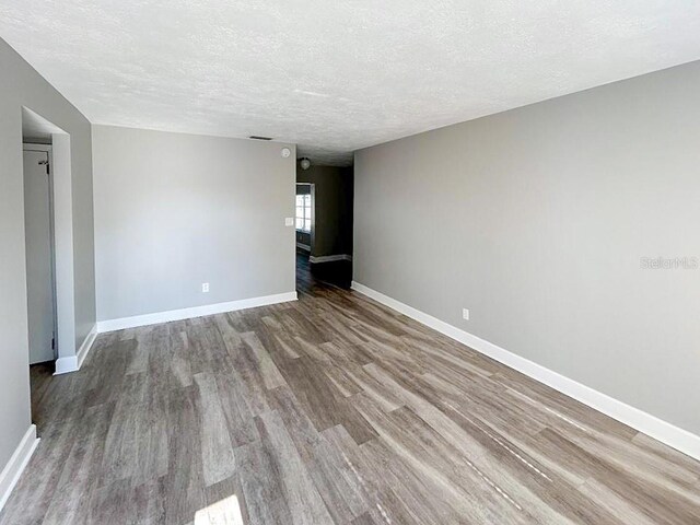 spare room with a textured ceiling and hardwood / wood-style floors