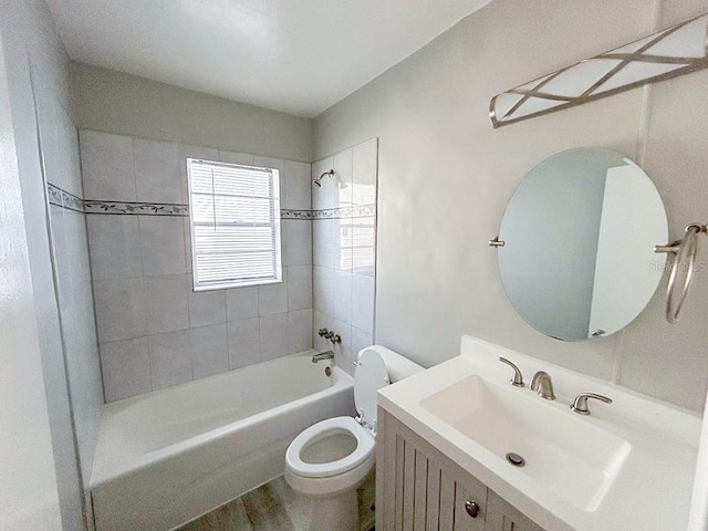 full bathroom featuring hardwood / wood-style flooring, tiled shower / bath combo, vanity, and toilet