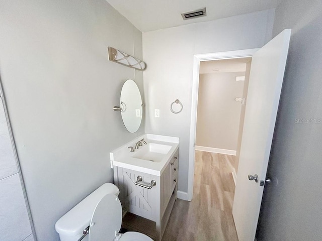 bathroom featuring large vanity, toilet, and hardwood / wood-style floors