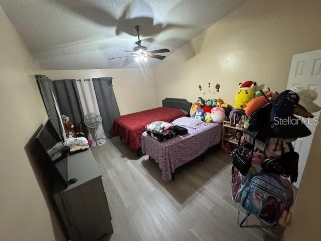 bedroom with vaulted ceiling, ceiling fan, hardwood / wood-style flooring, and a textured ceiling